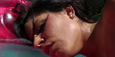 A solo babe is in the pool, playing with her pussy lips a lot