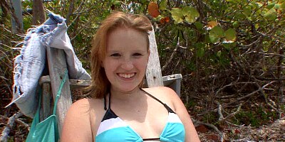 A smiling blue eyed honey is playing with a dick on the beach