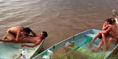 Horny people are having group sex on the beach in a small boat