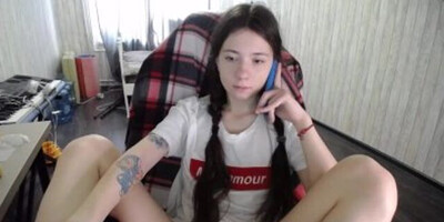 Teen girl with pigtails is on the phone while gently rubbing her pussy