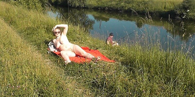 Naked mature woman is filmed while sunbathing by the river