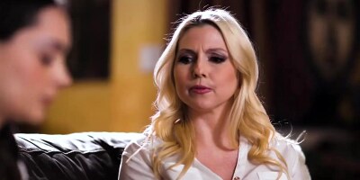 Christie S and Aften O on a brown coloured leather sofa in a lesbian scene together