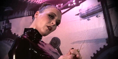 Dominatrix dressed in latex is playing with a toy
